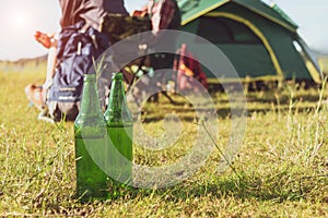 Close up of beer bottle in meadow while camping at outdoors. Holiday and Vacation concept. Adventure and outdoors theme