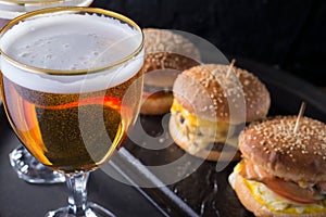 Close-up, beer glasses with craft dark and light beer with foam, against a background of burgers, with a variety of ingredients,