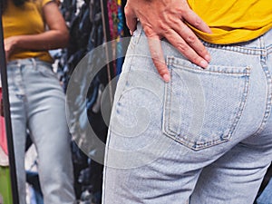 Close up behind the back of an Asian woman trying to shop jeans