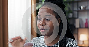 Close-up from behind ring light on face of dark-skinned woman of African-American descent, makeup artist talks to fans