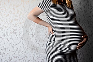 Close-up belly of a pregnant girl in a sundress in line