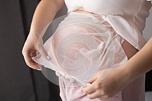 close-up belly of a pregnant woman applying a mask with cream from the appearance of stretch marks, pregnancy, body skin
