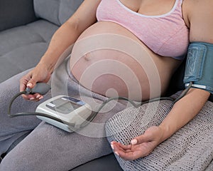 Close-up of the belly of a pregnant woman measuring blood pressure with a tonometer. Hypotension. photo