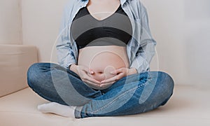 close up of the belly of a pregnant woman sitting on the couch