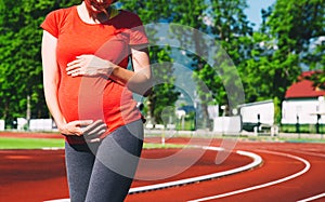 Close-up belly of pregnant woman on sport stadium.