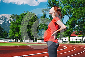 Close-up belly of pregnant woman on sport stadium.