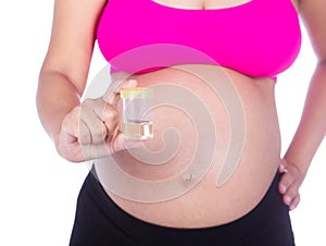 Close-up belly of pregnant woman with urine bottle on white back