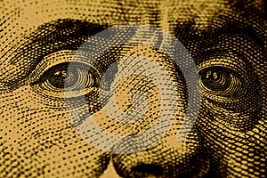 Close-up of Benjamin Franklin\'s eyes with a dollar sign in them