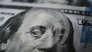 Close-up of Benjamin Franklin\'s eyes on a hundred dollar bill looking at the camera, macro photograph of a US banknote