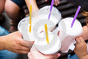 Close-up beverage of milkshakes for Summer. Family on walk drinking milkshakes