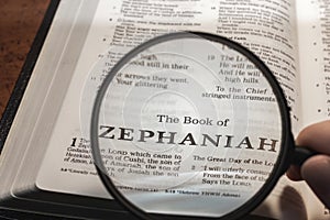 closeup of the book of Zephaniah from Bible or Torah using a magnifying glass to enlarge print. photo