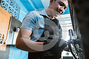 close up of a bicycle mechanic in apron and gloves installing axles