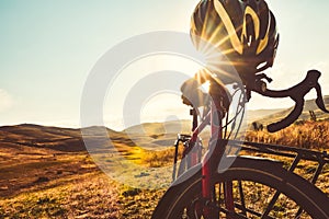 Close up bicycle stand in nature with sunflare peaks through helmet. Cinematic cycle wallpaper. Travel transport red bike