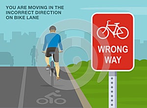 Close-up of a bicycle wrong way sign. Back view of a cyclist cycling on a bike lane.