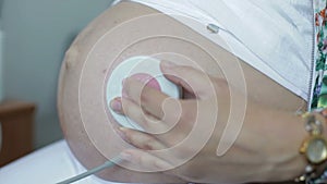 Close-up. The big belly of pregnant woman with cardio sensor.