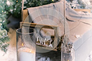 Close up of big candles in glass vases near swing in a snow-covered park