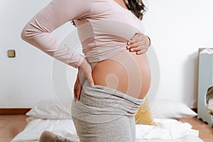 Close up of big expecting belly of pregnant woman in bed with hands touching. pregnancy, motherhood and expectation concept