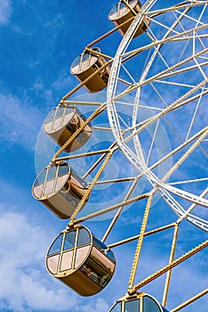 Close-up big gold modern ferris wheel against clear blue sky on background.