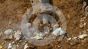 CLOSE UP Big industrial jackhammer pulsating and crushing rocks deep in the dirt