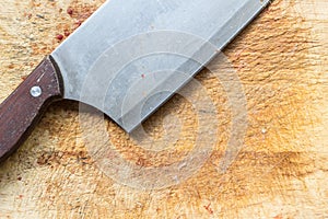 Close up big knife on rought wooden chopping block