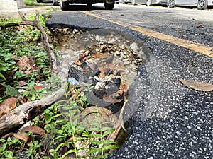 Close up of a big pothole at the edge of the road
