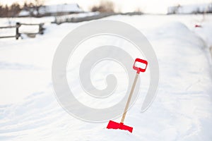 Close up of big red plastic showel in the process of removing snow in winter