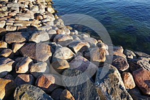 Close up of big stones of Baltic sea shore. Sunny day and dark green navy sea water in diagonal. Reidi tee, Tallinn