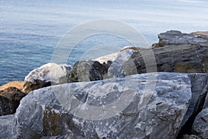 Close up of big stones of mediterranean sea shoe. Stone wave breakers of Italian coast on a sunny summer day.