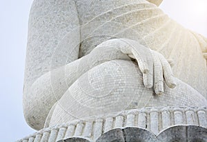 Close up of big white marble Buddha statue hand with cloudy sky background, Thailand