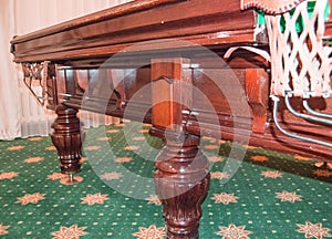 Close-up of a billiard table with a pocket. Wooden billiard table leg