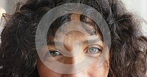 Close-up of a biracial woman with curly black hair and blue eyes