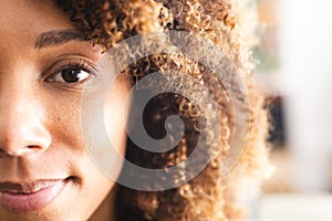 Close-up of a biracial woman with curly hair and warm brown eyes