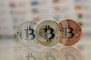 Close up of Bitcoins, gold bitcoin, silver bitcoin and bronze bitcoin with blurred background of world flags. reflection