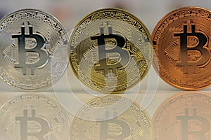 Close up of Bitcoins, gold bitcoin, silver bitcoin and bronze bitcoin with blurred background of world flags. reflection