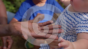Close-up of a black adult palm and a white child hand. Intergenerational interaction