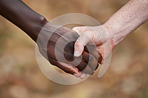 Close up of black african american and caucasian white people holding hands