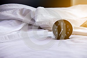 Close up of black alarm clock on the white bed