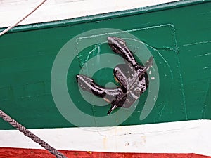 Close-up of black anchor on colorful ship hull