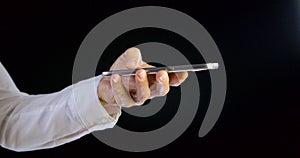 Close-up on a black background female hand with a mobile phone finger on the touch screen.