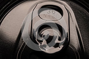Close-up of black beer or soda can pull ring macro. A macro image of black lid and pull ring, representing the