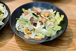 Close-up of bowl of caesar salad placed on wooden table