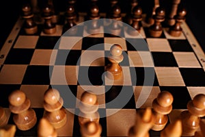 Close up of black chess pieces on board. Two rows of wooden figures on chessboard on black background. Concept of