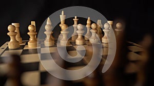 Close up of black chess pieces on board. Two rows of wooden figures on chessboard on black background. Concept of