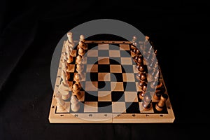 Close up of black chess pieces on board. Two rows of wooden figures on chessboard on black background. Concept of