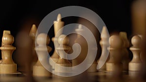 Close up of black chess pieces on board. Two rows of wooden figures on chessboard on black background. Concept of