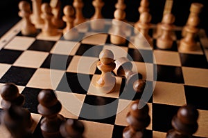 Close up of black chess pieces on board. Two rows of wooden figures on chessboard on black background. Concept of