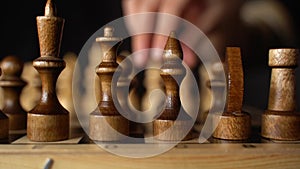 Close up of black chess pieces on board. Two rows of wooden figures on chessboard on black background. Concept of