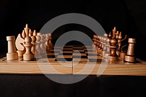 Close up of black chess pieces on board. Two rows of wooden figures on chessboard on black background. Concept of