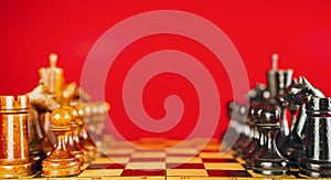 Close up of black chess pieces on board. Two rows of wooden figures on chessboard on red background. Concept of