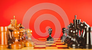 Close up of black chess pieces on board. Two rows of wooden figures on chessboard on red background. Concept of